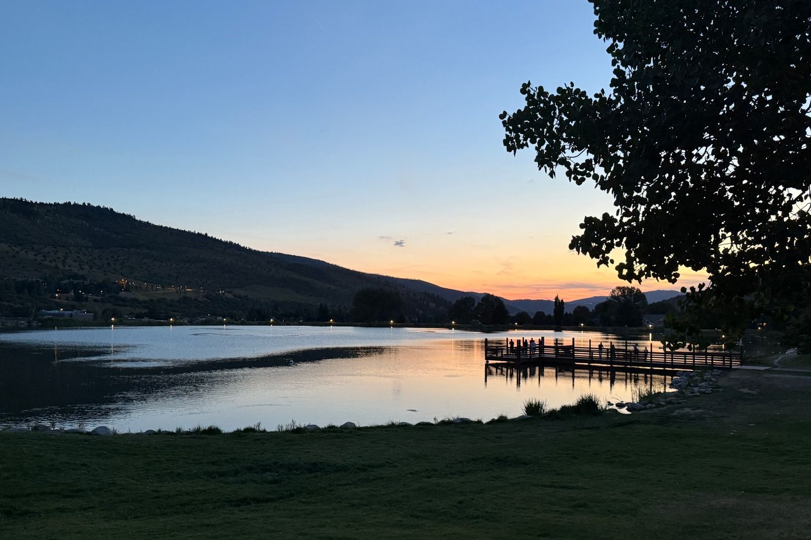Sunset over Nottingham Lake in Avon, with mountains, a wooden dock and trees along the shoreline.