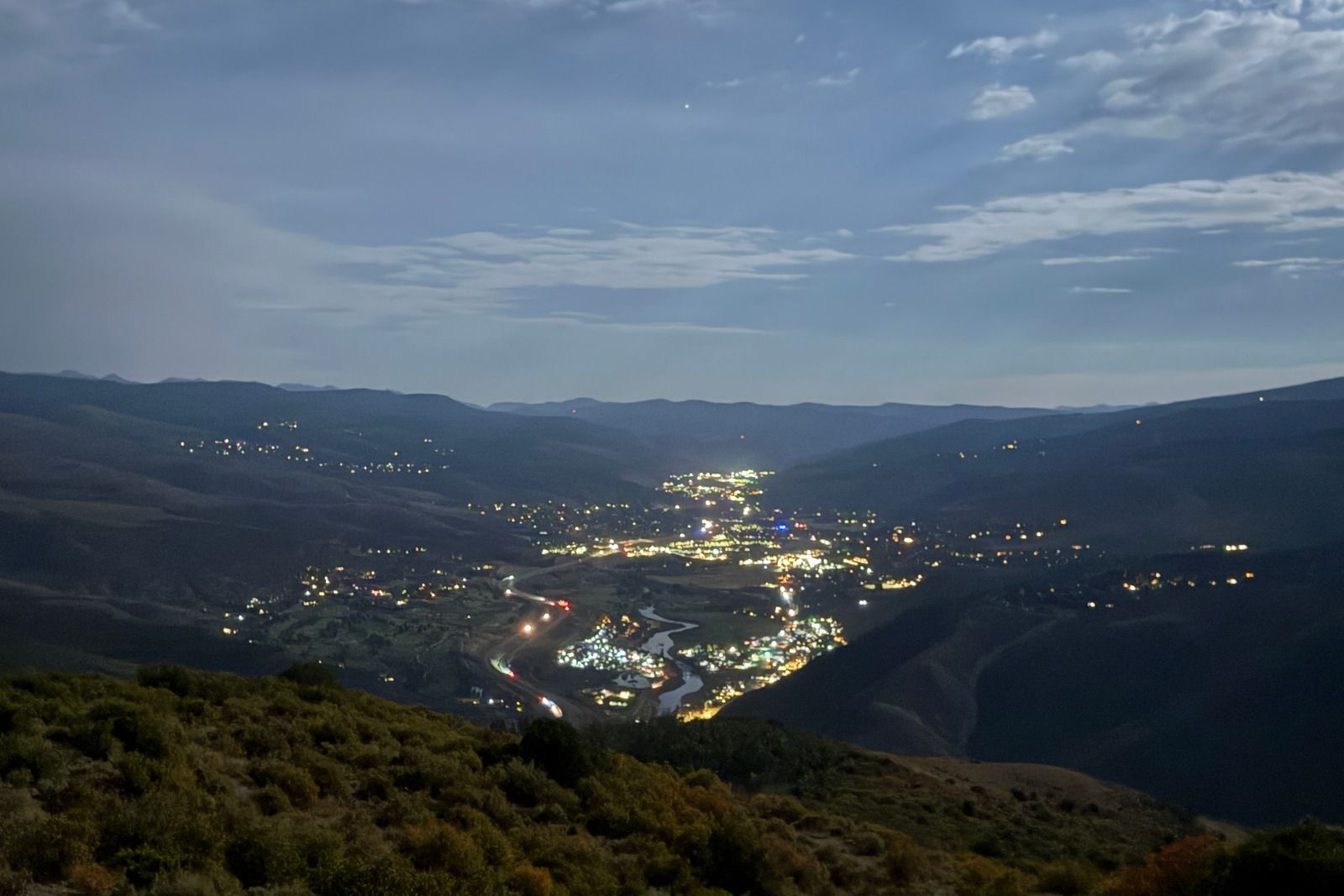 Edwards at dusk, with illuminated roads and buildings winding through a valley beneath mountain ridges and a cloudy sky.